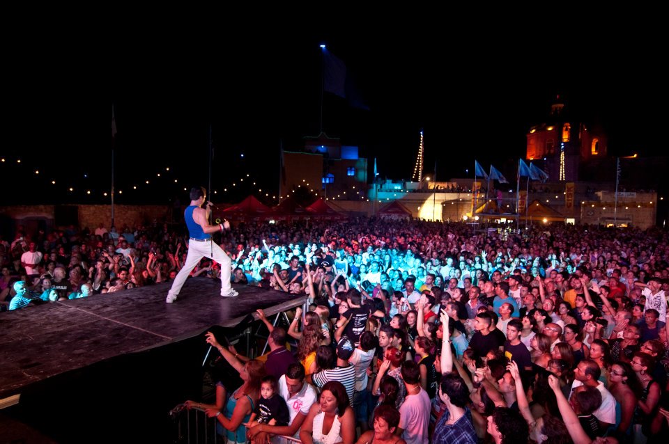 UK Queen tribute band lead singer performing for an enthusiastic crowd in Malta during a live concert.